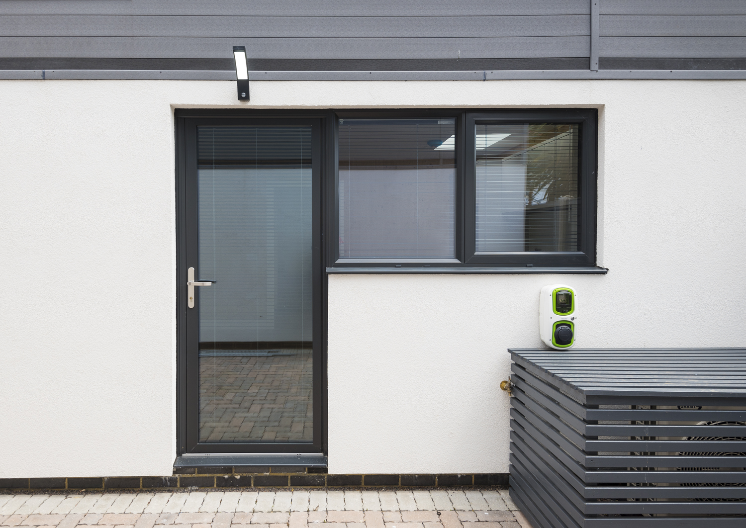 Back door of a modern build home with a electric car charger to the side